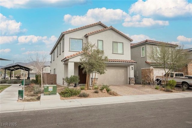 mediterranean / spanish home with a garage, a tiled roof, decorative driveway, and stucco siding