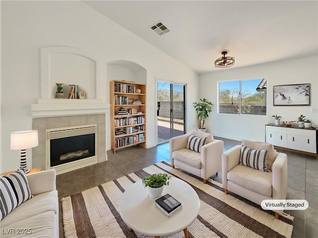 tiled living room featuring a tiled fireplace and vaulted ceiling