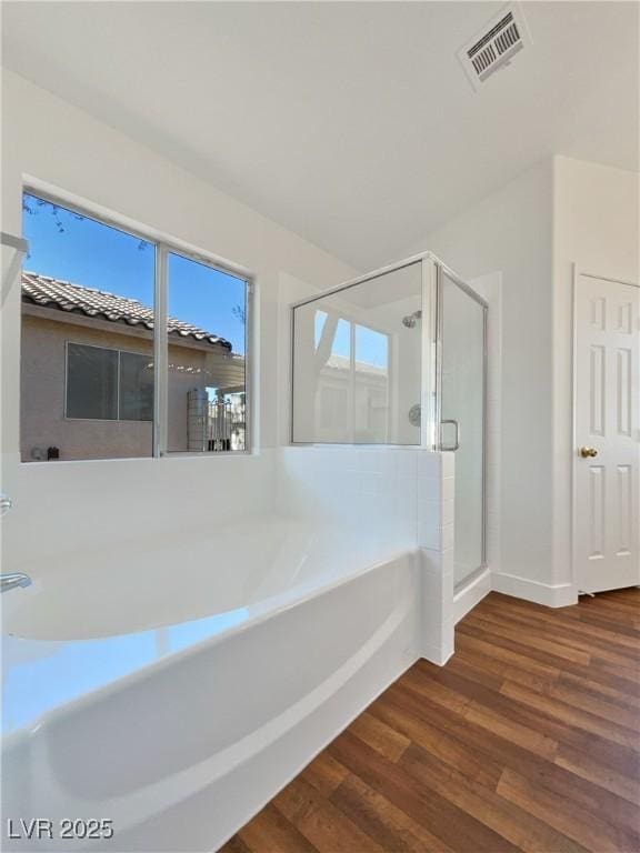 bathroom featuring plus walk in shower and wood-type flooring