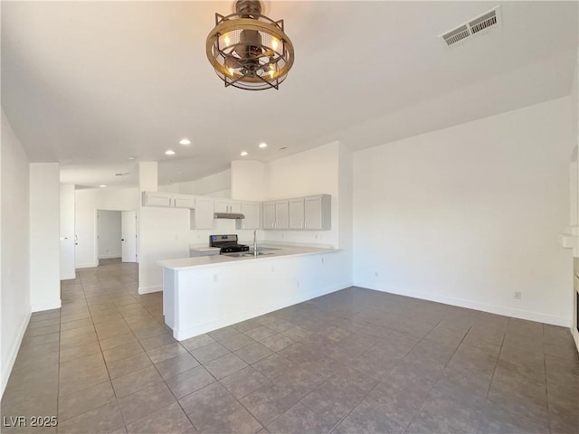 kitchen with sink, stainless steel range, tile patterned flooring, and kitchen peninsula