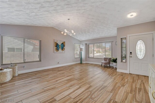 foyer entrance with lofted ceiling, a textured ceiling, and a chandelier