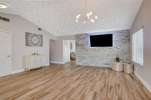 unfurnished living room with a textured ceiling, a notable chandelier, and light hardwood / wood-style flooring