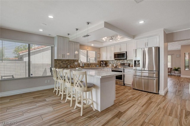 kitchen with stainless steel appliances, white cabinetry, backsplash, and pendant lighting