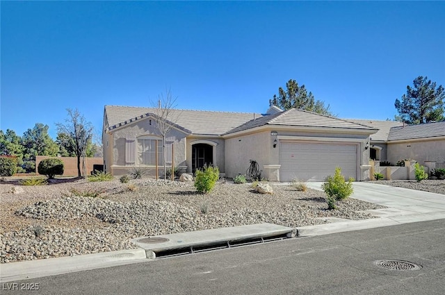 view of front of property featuring concrete driveway, a tiled roof, an attached garage, and stucco siding