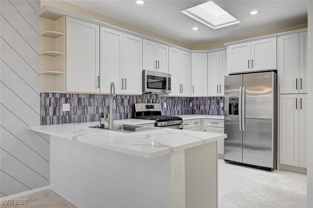 kitchen with stainless steel appliances, a peninsula, a skylight, a sink, and open shelves