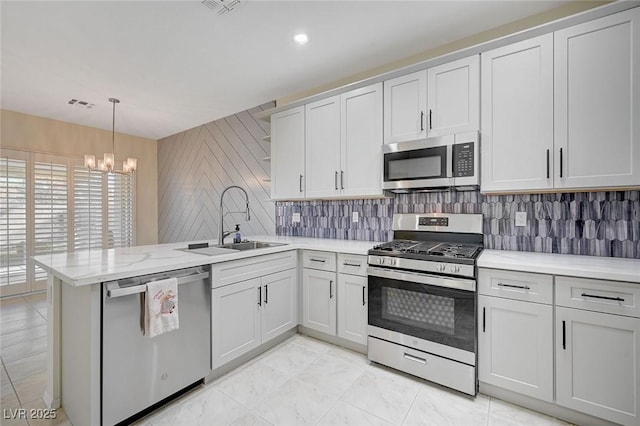 kitchen with white cabinetry, kitchen peninsula, pendant lighting, a notable chandelier, and appliances with stainless steel finishes