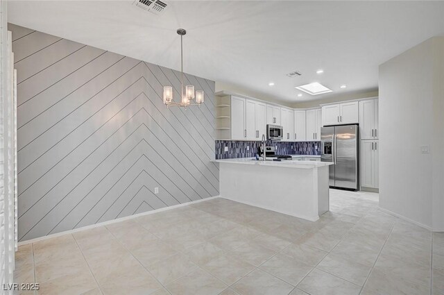 kitchen with stainless steel appliances, decorative light fixtures, white cabinetry, tasteful backsplash, and kitchen peninsula