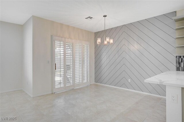 unfurnished dining area featuring an inviting chandelier, wood walls, and light tile patterned floors