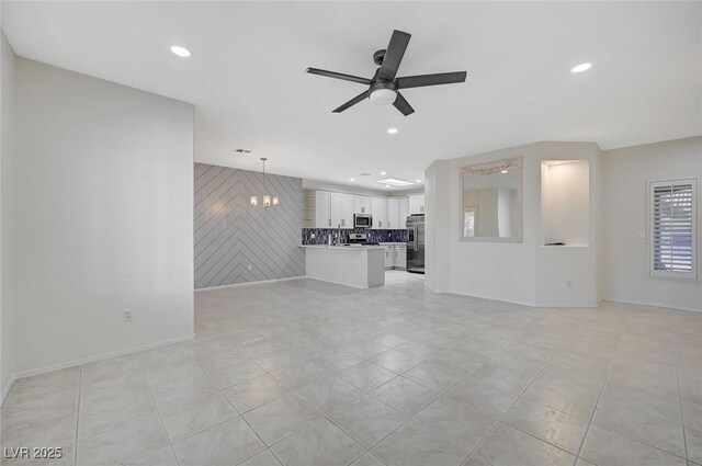 unfurnished living room with ceiling fan with notable chandelier and light tile patterned floors