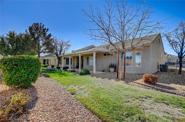 rear view of property with a lawn and central air condition unit