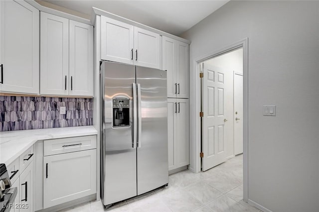 kitchen with white cabinets, light stone counters, stove, decorative backsplash, and stainless steel fridge with ice dispenser