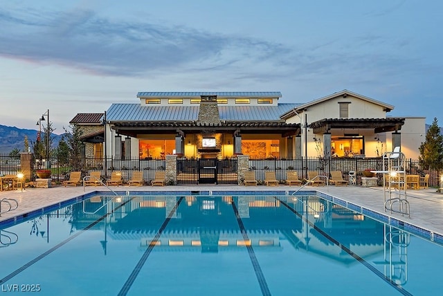 pool at dusk with a patio area and a mountain view