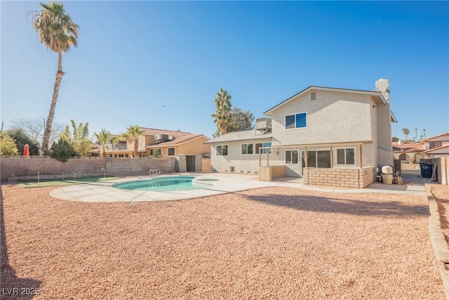 rear view of house with a fenced in pool and a patio area