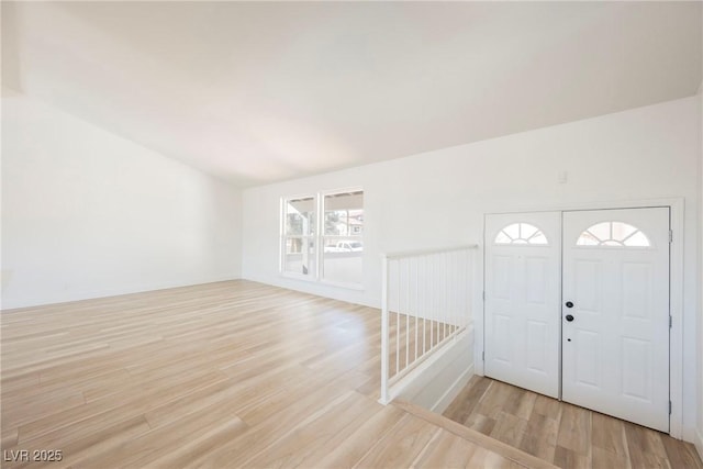 foyer entrance with light wood-type flooring and vaulted ceiling