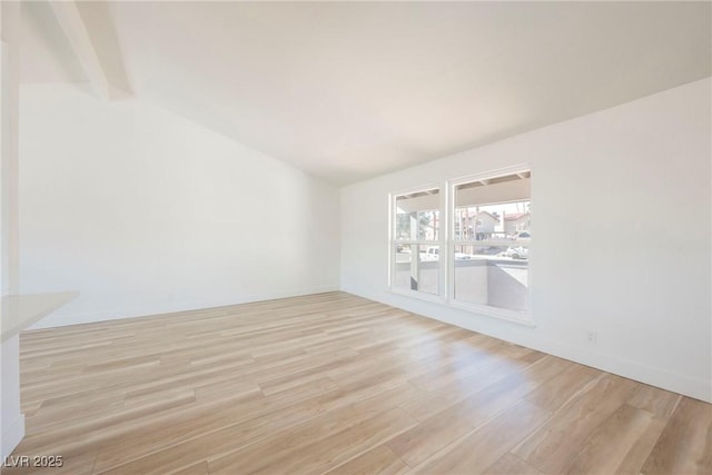 empty room with lofted ceiling with beams and light hardwood / wood-style floors