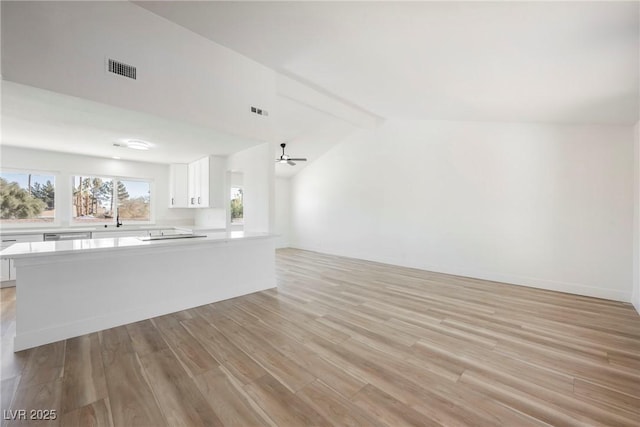 unfurnished living room with ceiling fan, light hardwood / wood-style flooring, and vaulted ceiling with beams