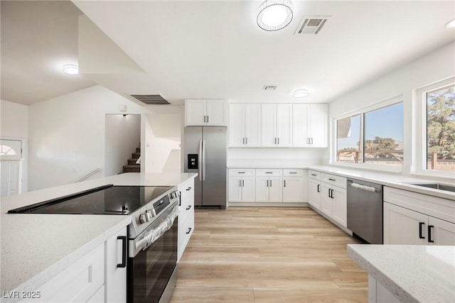 kitchen featuring appliances with stainless steel finishes, light hardwood / wood-style flooring, and white cabinets