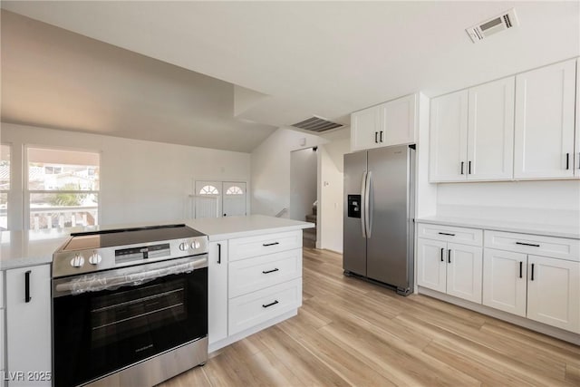 kitchen with lofted ceiling, white cabinets, light hardwood / wood-style floors, and appliances with stainless steel finishes