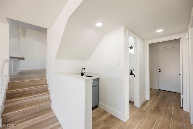 interior space featuring lofted ceiling, light hardwood / wood-style flooring, and sink