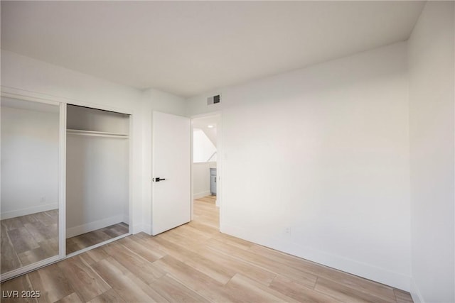 unfurnished bedroom with light wood-type flooring and a closet