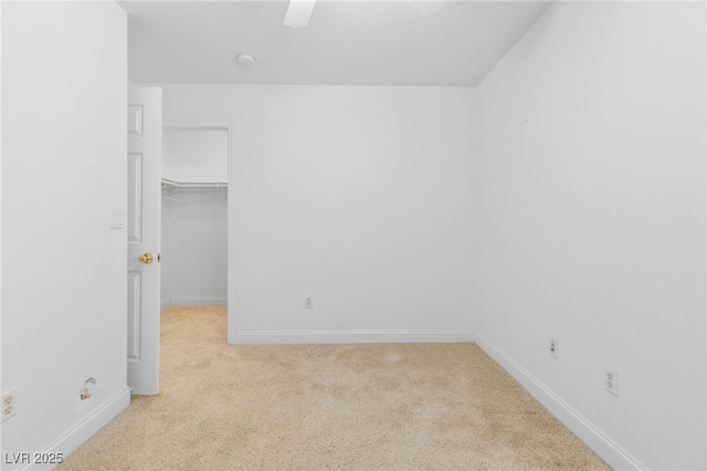 unfurnished bedroom featuring a closet, ceiling fan, a spacious closet, and light carpet