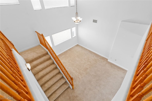 stairway featuring a high ceiling, a notable chandelier, and carpet flooring