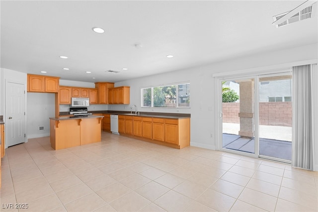 kitchen with white appliances, a kitchen breakfast bar, a kitchen island, sink, and light tile patterned flooring