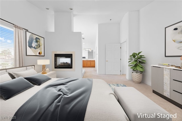 bedroom featuring a multi sided fireplace, ensuite bathroom, a high ceiling, and light carpet