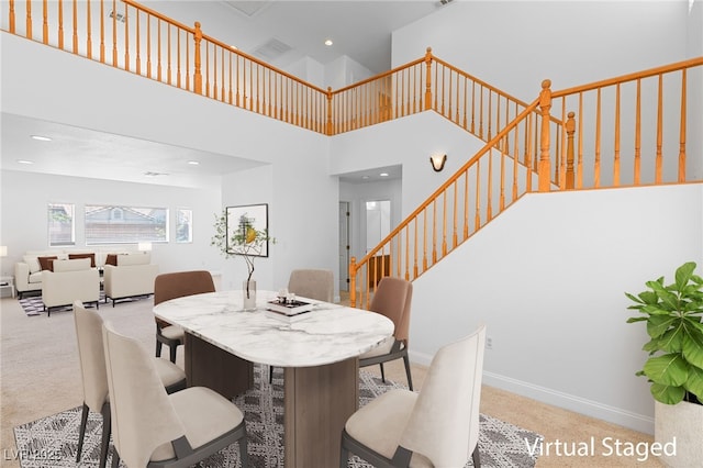 carpeted dining room featuring a towering ceiling