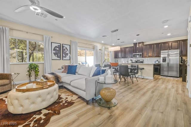 living room featuring ceiling fan, light hardwood / wood-style flooring, a healthy amount of sunlight, and sink