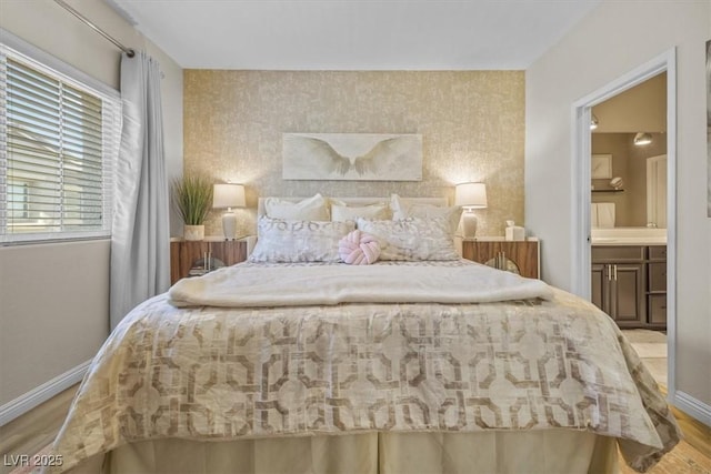 bedroom with light hardwood / wood-style flooring and connected bathroom