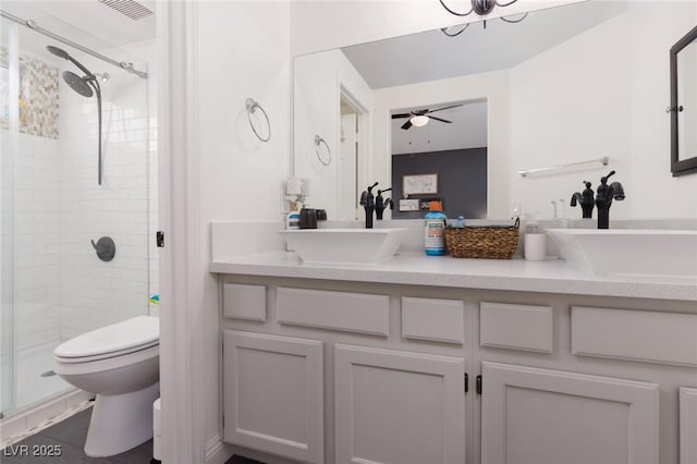 bathroom with toilet, a shower with door, vanity, and ceiling fan