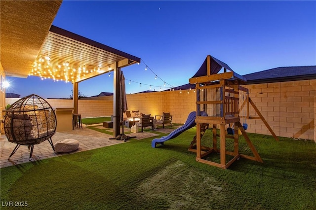 playground at dusk featuring a patio area and a yard