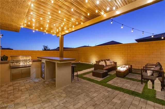 patio terrace at dusk featuring an outdoor living space with a fire pit, grilling area, area for grilling, and a bar