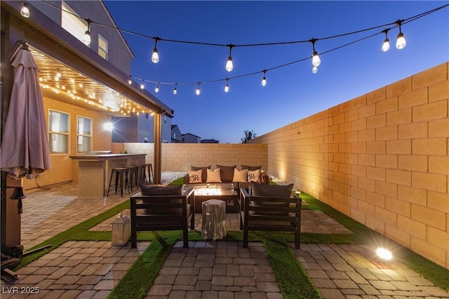 patio terrace at dusk featuring an outdoor living space with a fire pit and exterior bar