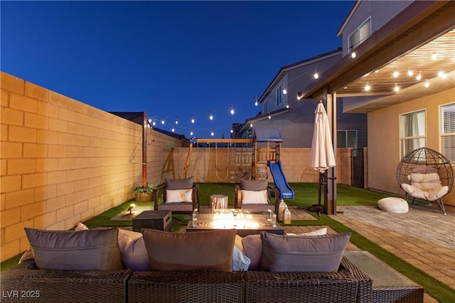 patio at night featuring an outdoor living space with a fire pit