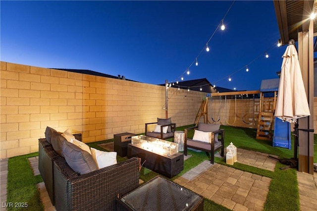 patio at night with an outdoor living space with a fire pit