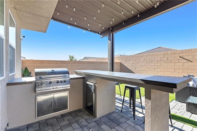 view of patio with an outdoor kitchen, wine cooler, exterior bar, and a grill