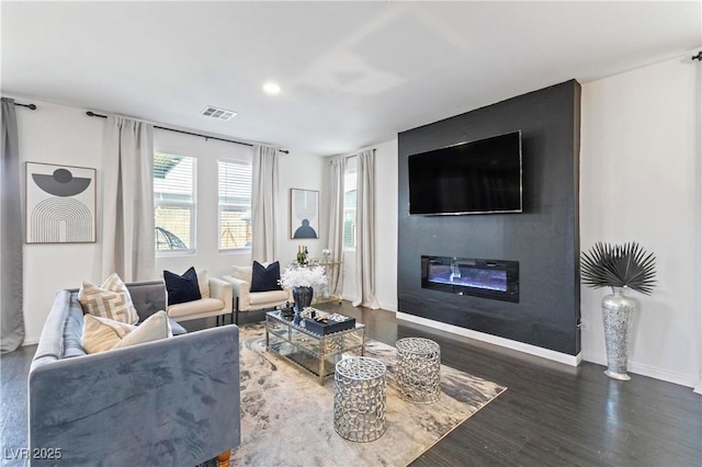 living room with dark hardwood / wood-style flooring and a large fireplace