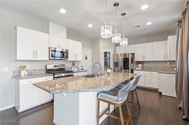 kitchen with a center island with sink, appliances with stainless steel finishes, white cabinetry, and sink