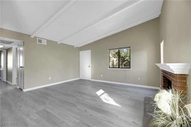 unfurnished living room with a brick fireplace, hardwood / wood-style flooring, and vaulted ceiling with beams