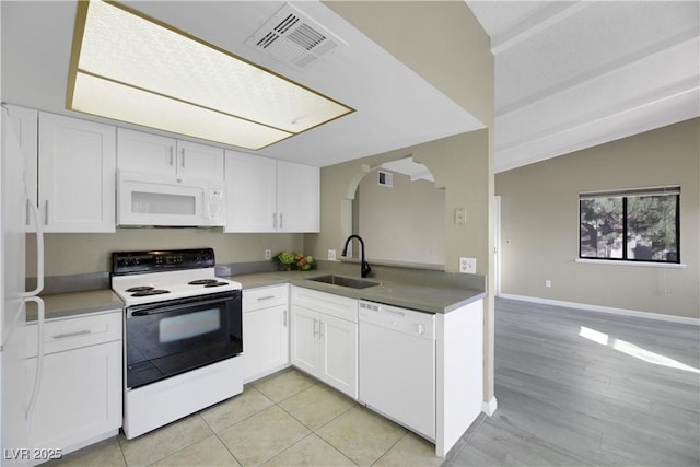 kitchen featuring sink, white cabinetry, vaulted ceiling, white appliances, and light tile patterned floors