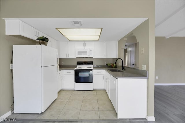 kitchen featuring white appliances, white cabinets, light tile patterned floors, and sink