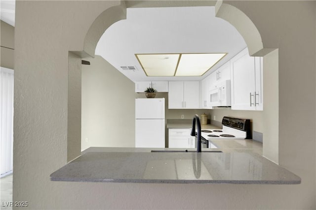 kitchen with sink, white cabinets, light stone counters, white appliances, and kitchen peninsula