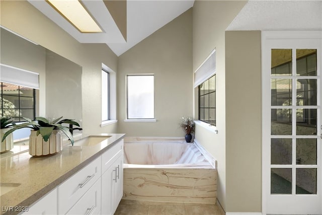 bathroom with tile patterned floors, a tub, lofted ceiling, and vanity