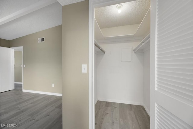 spacious closet featuring hardwood / wood-style floors and lofted ceiling