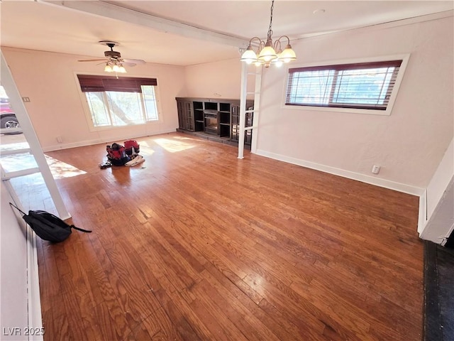 unfurnished living room featuring ceiling fan with notable chandelier and hardwood / wood-style flooring