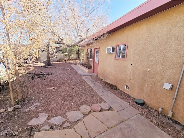 view of home's exterior featuring an AC wall unit and a patio area