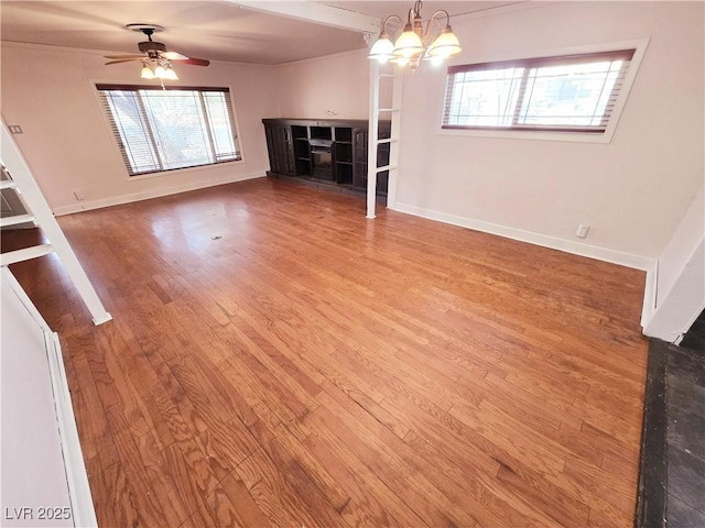 unfurnished living room with ceiling fan with notable chandelier and hardwood / wood-style floors