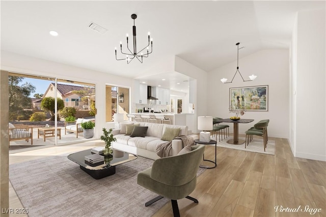 living room featuring light hardwood / wood-style floors, an inviting chandelier, and lofted ceiling